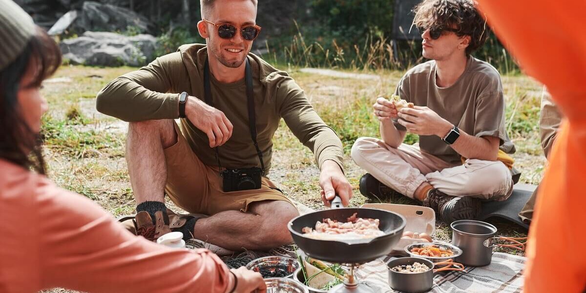 caucasian-man-frying-eggs-on-burner-at-camping