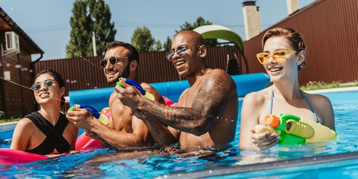 happy-multiethnic-friends-playing-with-water-guns