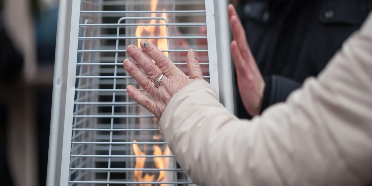 woman warmming hands in front of a gas heater